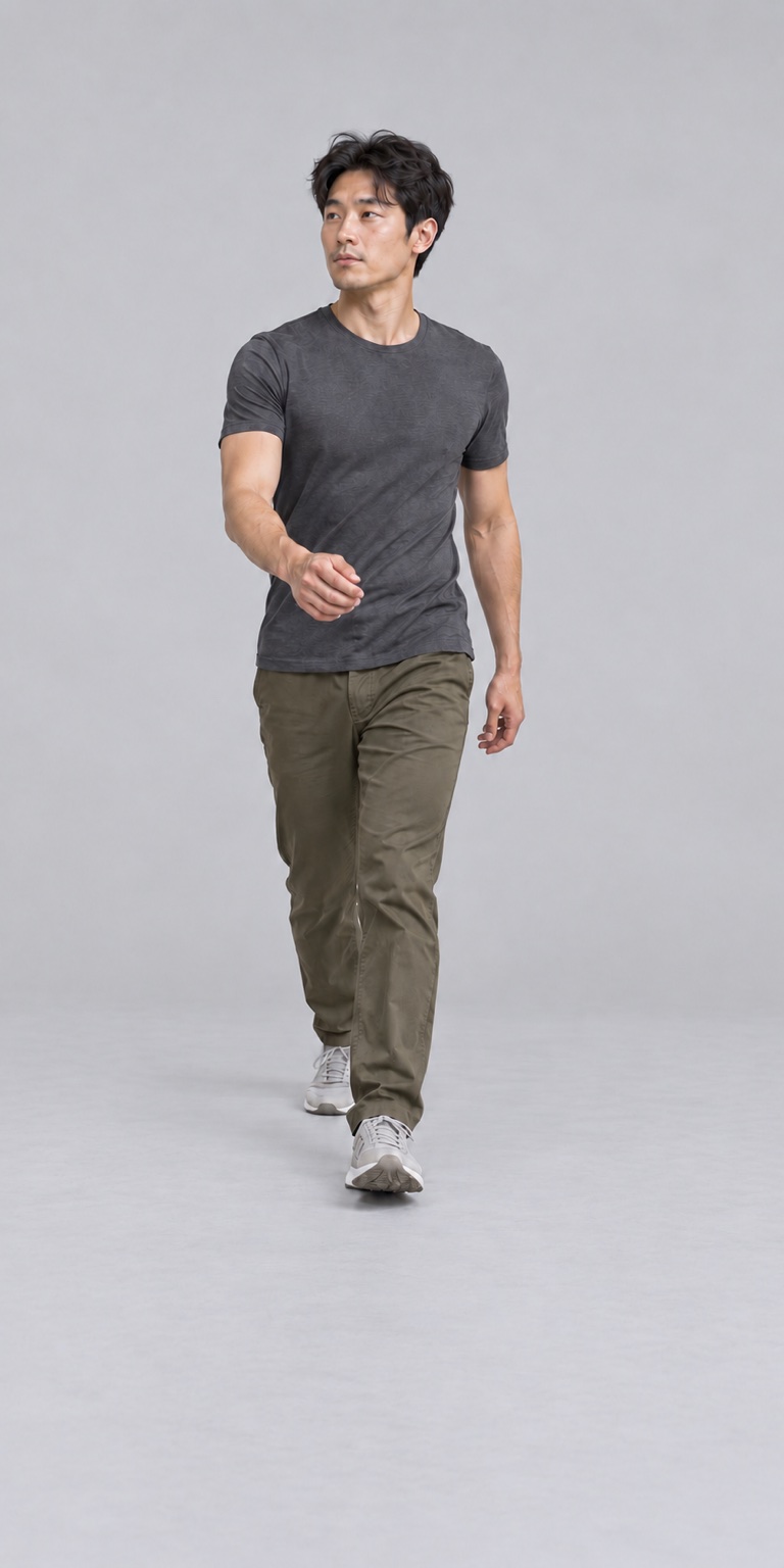 Clothed man stepping forward in a gray studio while turning his head